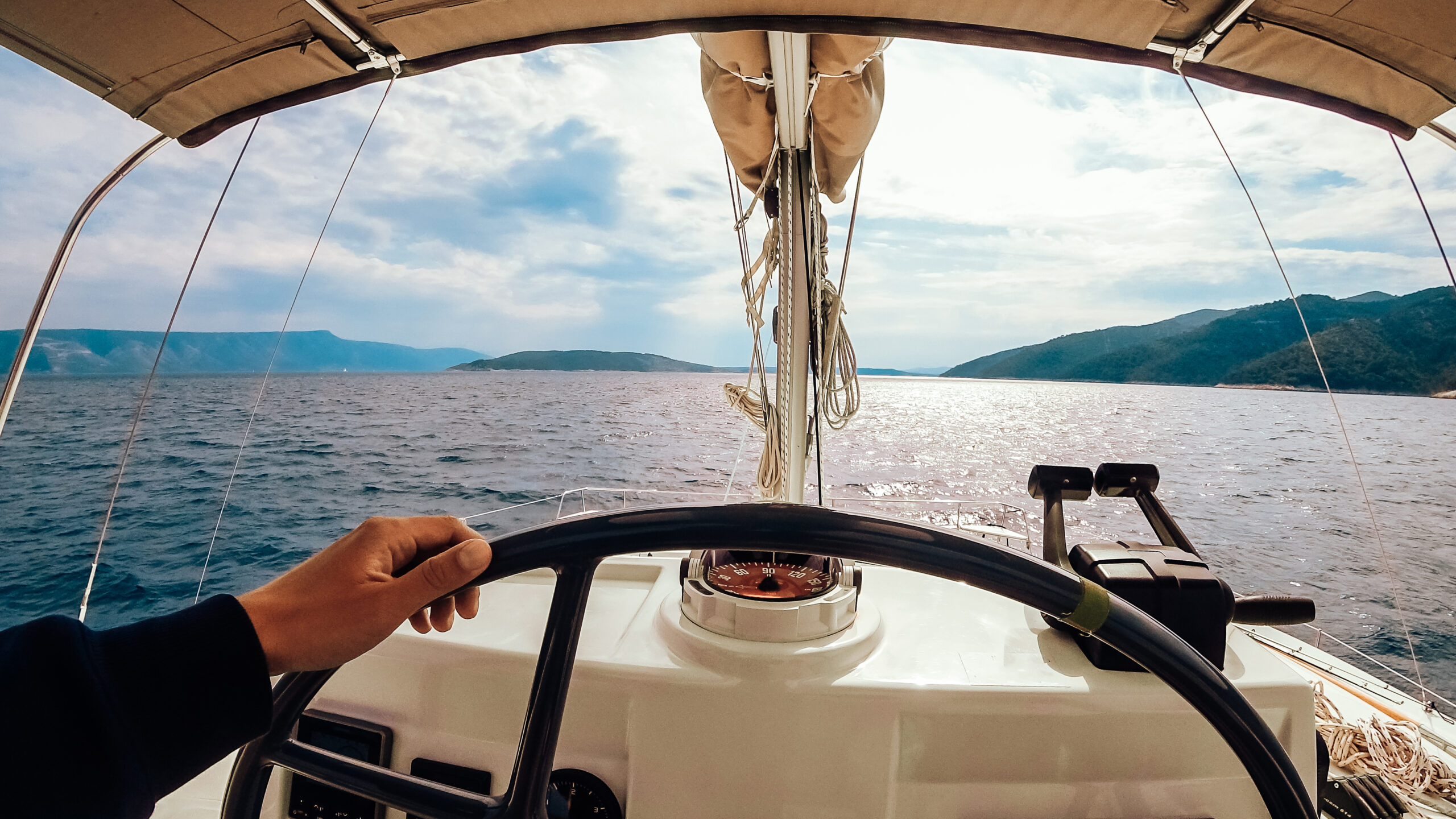 Ship control panel with steering wheel on the captain bridge. Men's hand controls the yacht